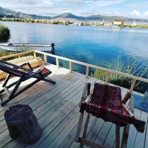 a wooden deck with a bench and a chair on a body of water at Uros Titicaca Khantaniwa Lodge in Puno