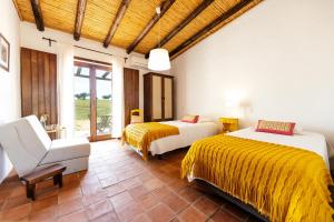 1 dormitorio con 2 camas, silla y ventana en Agroturismo Flores do Campo, en Vila Verde de Ficalho