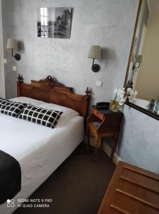 a bedroom with a bed and a table and a mirror at Hôtel Verlaine in Paris