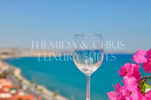 Luxury Penthouse 1BR-Seafront-Seasonal Pool-Central في لارنكا: كوب من النبيذ بجانب بعض الزهور الزهرية
