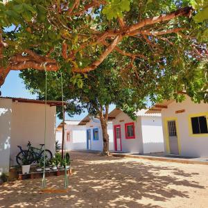 a swing under a tree in front of buildings at Chales do delta Piauí in Parnaíba