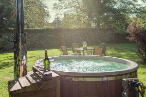 a hot tub with a table and a bottle of wine at Herons Wood at Greyfriars in Winchelsea