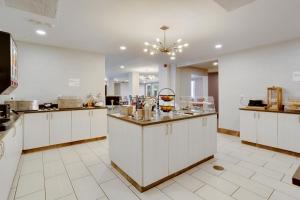 a large kitchen with white cabinets and a counter at Orangewood Inn & Suites Kansas City Airport in Kansas City