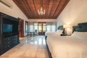 a bedroom with two beds and a flat screen tv at Maison Larimar-Walking Distance to the Marina at Casa de Campo in La Romana