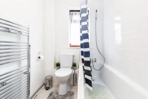 uma casa de banho branca com um WC e um chuveiro em Cosy 2 bedroom house! Dagenham! Free parking em Goodmayes