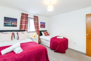 um quarto com 2 camas com lençóis vermelhos e uma janela em Cosy 2 bedroom house! Dagenham! Free parking em Goodmayes