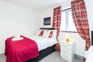 um quarto com uma cama vermelha e uma janela em Cosy 2 bedroom house! Dagenham! Free parking em Goodmayes