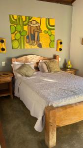 1 dormitorio con cama de madera y una pintura en la pared en Pousada Fecho da Serra en Capitólio