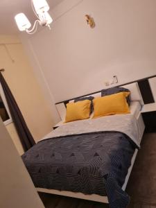 - une chambre avec un grand lit et des oreillers jaunes dans l'établissement The FFG House - Appartements meublés Douala Cite des palmiers, Bonamoussadi, à Douala