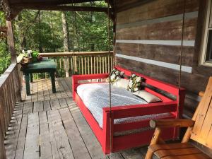 a red swing on a porch of a cabin at R&R Retreat in Sunshine