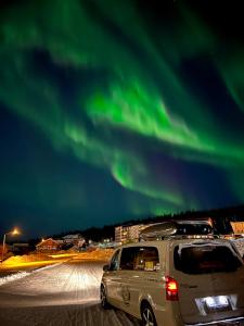 Um SUV está estacionado sob as luzes verdes do norte. em Salomon Chalet 7207 - Parivuoteellinen makuuhuone ja lisäksi makuualkovi - Täydellinen pariskunnille ja perheille em Ylläsjärvi