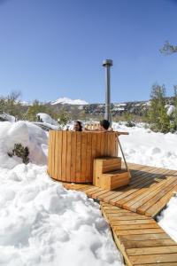 dwoje ludzi siedzących na drewnianym tarasie w śniegu w obiekcie MI Lodge Las Trancas Hotel & Spa w mieście Las Trancas