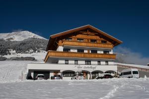 a building with cars parked in front of it in the snow at Apart Sattelkopf in Fiss