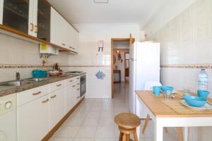 a kitchen with white cabinets and blue bowls on a table at Apartamento Sea Shell in Albufeira