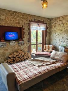 um quarto com uma parede de pedra, uma cama e uma televisão em Appartamento 14 em Bellagio