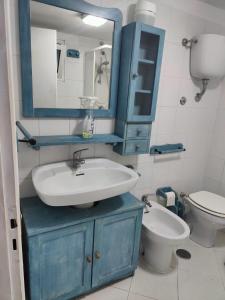y baño con lavabo azul y aseo. en ZÍ MARIO Suite degli Ospiti - Roma Ostia Antica, en Ostia Antica