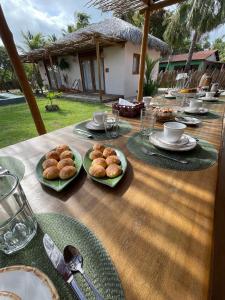 uma mesa de madeira com pratos de comida em Casa Rosa Atins em Atins