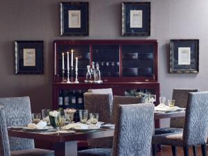 una sala da pranzo con tavolo, sedie e bottiglie di vino di Hotel Du Lac Congress Center & Spa a Ioannina
