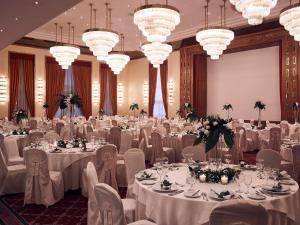 a banquet hall with white tables and chairs and chandeliers at Hotel Du Lac Congress Center & Spa in Ioannina