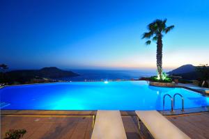 a swimming pool at night with a palm tree at Stefanos Village Hotel in Plakias