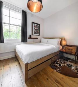 a bedroom with a large bed and a window at Traditional Victorian 2 bed in cobbled street + mod cons - Full home in London