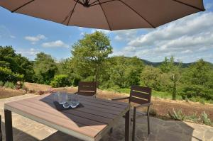 einen Holztisch mit zwei Stühlen und einem Sonnenschirm in der Unterkunft Appartament Rosmarino - Cignella Resort in Osteria Delle Noci