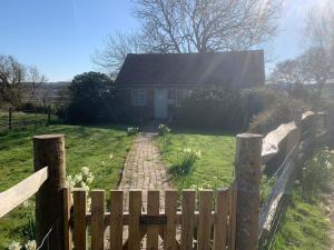 una valla de madera frente a una casa en The Piggery, a perfect country hideaway, en Crowhurst