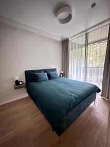 a bedroom with a green bed with a large window at Naujai įrengti pušyno apartamentai - bekontaktis įėjimas in Birštonas