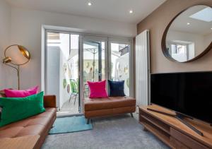 een woonkamer met een tv, een bank en een spiegel bij Corner Cottage in Brighton & Hove