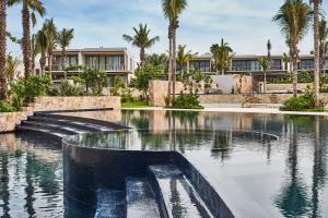 a swimming pool in front of a building with palm trees at Susurros del Corazón, Auberge Resorts Collection in Cruz de Huanacaxtle