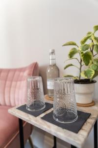 dos vasos en una mesa de madera con una botella. en House Arundel en Arundel