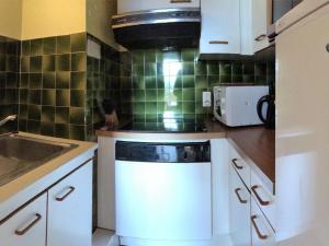 eine Küche mit weißen Schränken und einem Geschirrspüler in der Unterkunft Appart 8 pers à 150m des pistes, 2 chambres - FR-1-416-34 in La Toussuire