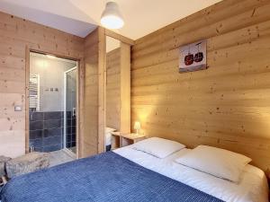 a bedroom with a wooden wall with a bed and a shower at Appartement lumineux face aux pistes, 3 chambres, 6 pers., centre station, 73300 Fontcouverte-la-Toussuire - FR-1-416-35 in La Toussuire