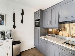 eine Küche mit weißen Schränken und einer Spüle und Utensilien in der Unterkunft Appartement moderne 3* 8 pers, 46 m², Sud, proche pistes - FR-1-416-78 in La Toussuire + 6 Fotos