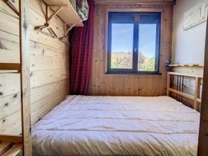 ein Bett in einem Holzzimmer mit Fenster in der Unterkunft Appartement moderne 3* 8 pers, 46 m², Sud, proche pistes - FR-1-416-78 in La Toussuire