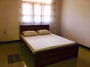 1 cama con 2 almohadas en una habitación con ventana en st anns holiday home negombo en Negombo