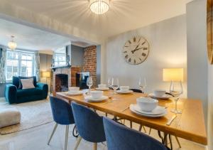 uma sala de jantar com mesa e cadeiras e um relógio em Pebble Beach Cottage em Rottingdean