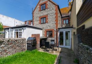a brick house with a grill in a yard at Pebble Beach Cottage in Rottingdean