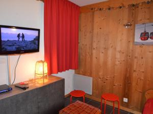 ein Wohnzimmer mit einem TV und zwei roten Stühlen in der Unterkunft Studio Les Menuires, 1 pièce, 4 personnes - FR-1-452-22 in Les Menuires