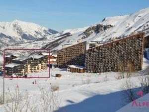 un gran edificio en la nieve con montañas en el fondo en Studio Les Menuires, 1 pièce, 4 personnes - FR-1-452-22, en Les Menuires