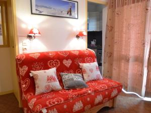- un canapé rouge avec des oreillers dans l'établissement Appartement Les Menuires, 2 pièces, 4 personnes - FR-1-452-28, aux Menuires