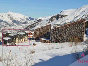 a large building in the snow with mountains in the background at Studio cabine rénové pour 4 pers, balcon, animaux admis - FR-1-452-55 in Les Menuires
