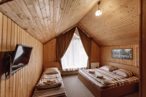 a bedroom with two beds and a tv in a room at Toga cottage in Yablunytsya