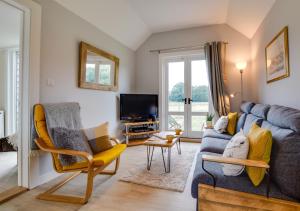 sala de estar con sofá azul y sillas amarillas en The Bolthole and Warren, en Biddenden