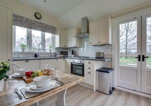 a kitchen with white cabinets and a wooden table at The Bolthole and Warren in Biddenden