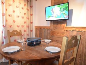 una mesa de madera con platos y TV en una habitación en Studio Les Menuires, 1 pièce, 3 personnes - FR-1-452-85, en Les Menuires