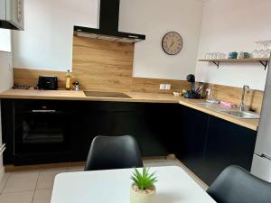 a kitchen with a table and a clock on the wall at La Parisienne - 80m2 in Vierzon