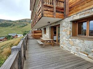 a wooden porch of a building with a picnic table at Appartement neuf pour 6 pers. avec parking, balcon et sur pistes - FR-1-416-186 in La Toussuire