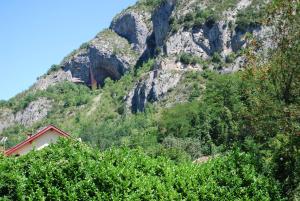 Une montagne avec une maison rouge devant elle dans l'établissement Les Terrasses De Castelmerle, à Niaux