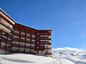 un bâtiment dans la neige avec des montagnes en arrière-plan dans l'établissement Appartement Les Menuires, 3 pièces, 6 personnes - FR-1-452-276, aux Menuires